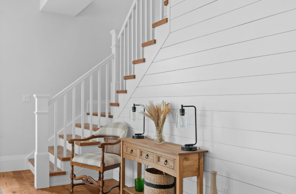 Entry staircase with white shiplap wall, wood treads, and styled console for builder photography in Kingston Ontario