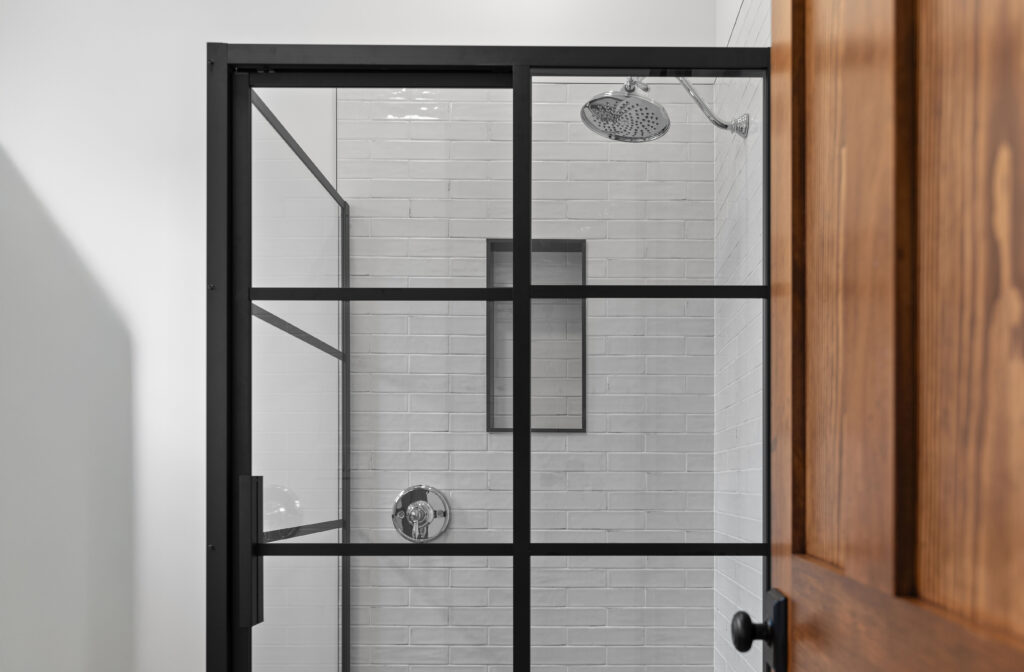 Shower with black grid glass, white tile, and rain head showcasing bathroom finish quality
