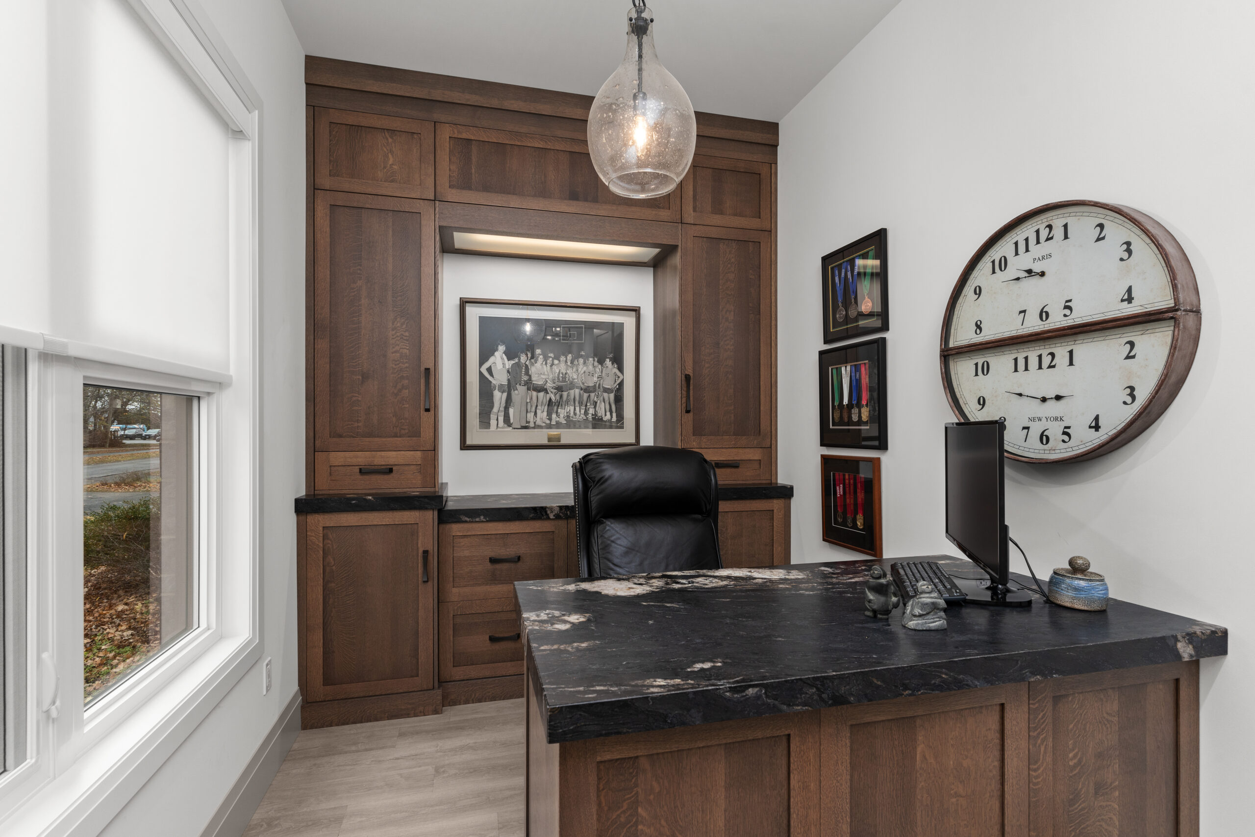 Built-in wood cabinetry home office with black countertop and large wall clock photographed for a Kingston builder