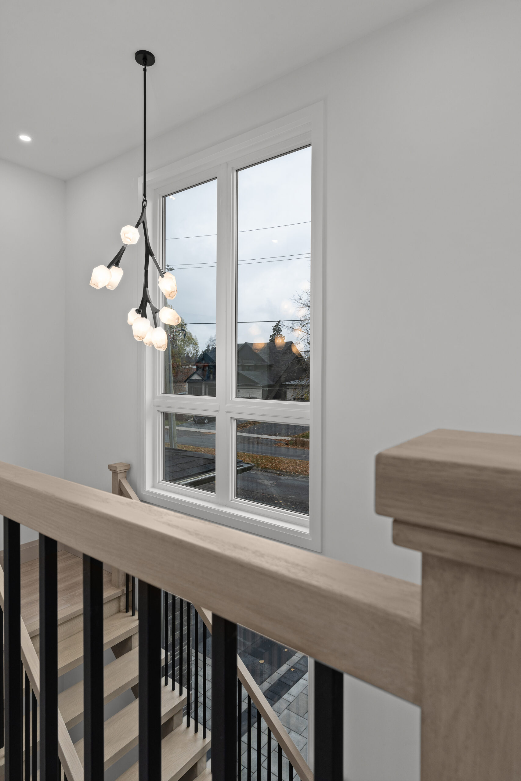 Custom staircase with black spindles and modern pendant light photographed for a Kingston home builder portfolio