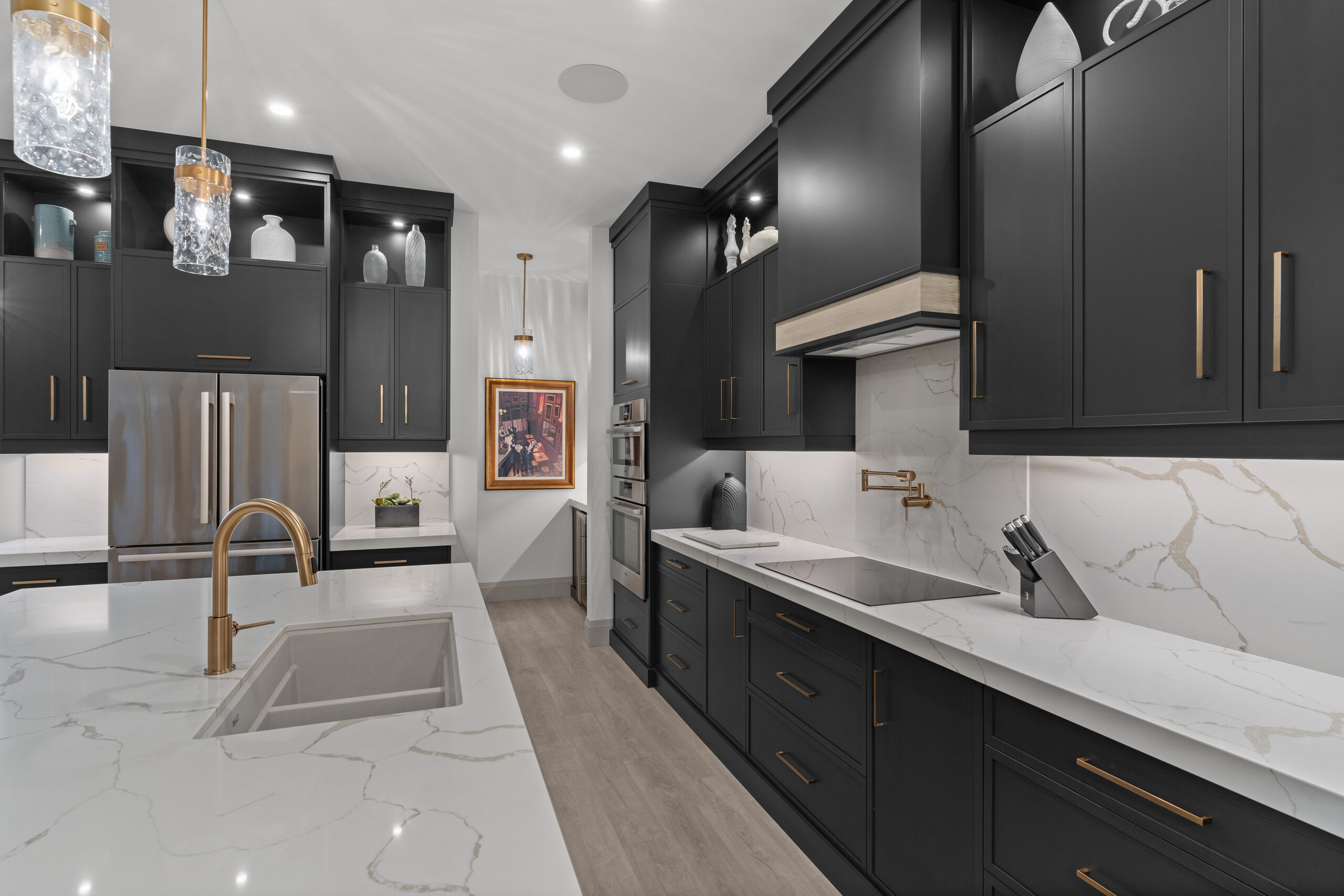 Custom kitchen with dark cabinetry, gold fixtures, and white island countertop photographed for a Kingston builder portfolio