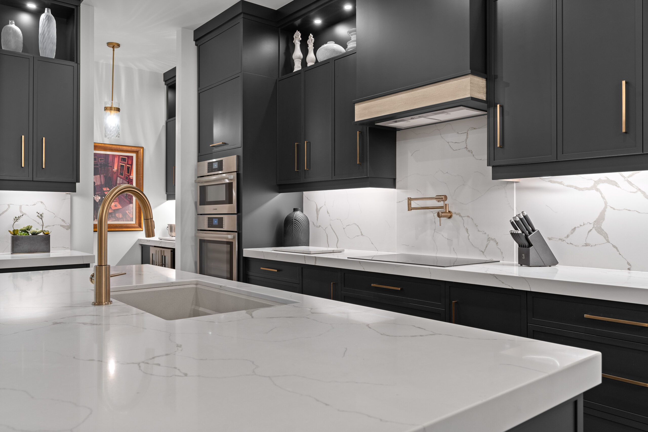 Custom kitchen with dark cabinetry, gold fixtures, and white island countertop photographed for a Kingston builder portfolio