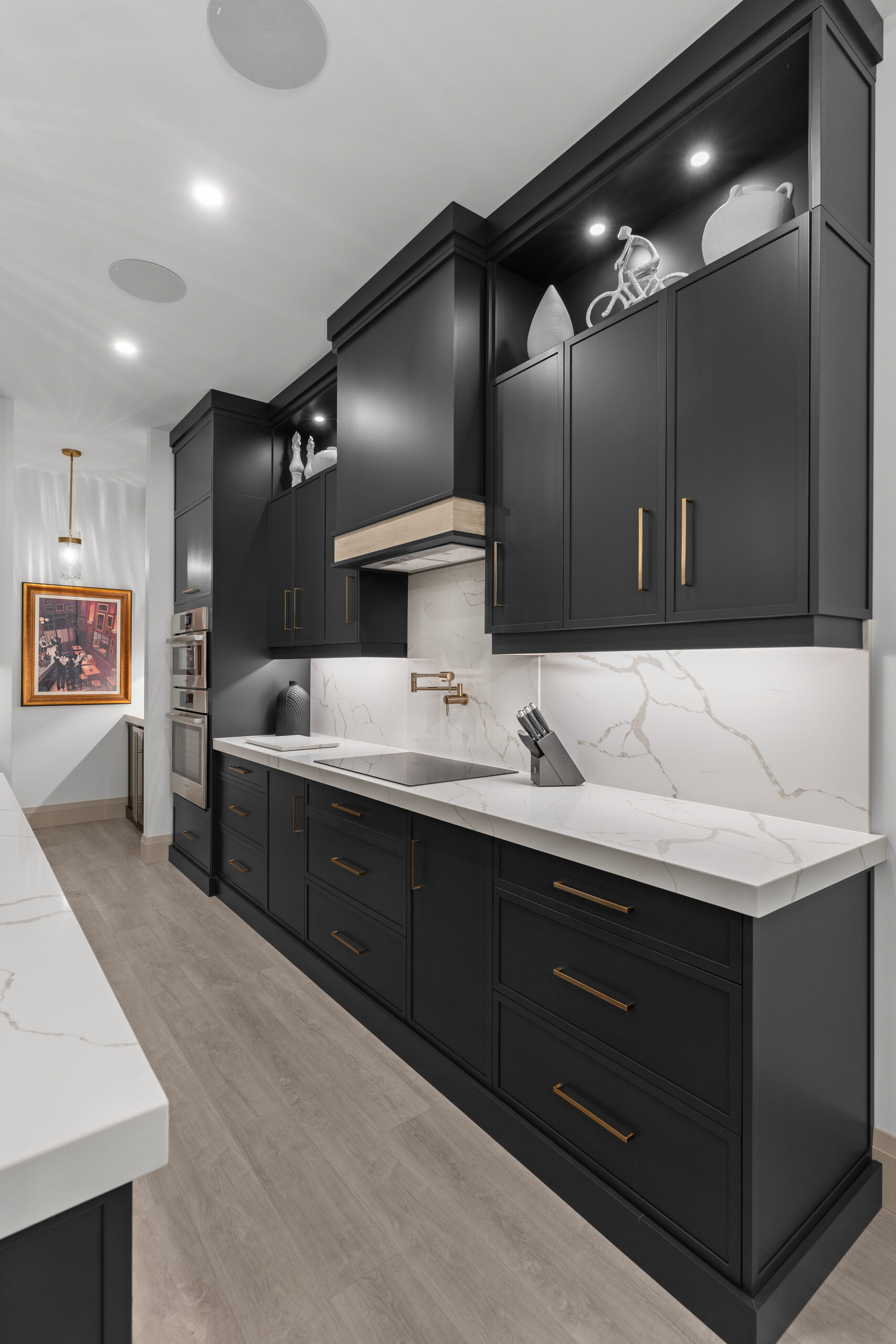 Custom kitchen with dark cabinetry, gold fixtures, and white island countertop photographed for a Kingston builder portfolio