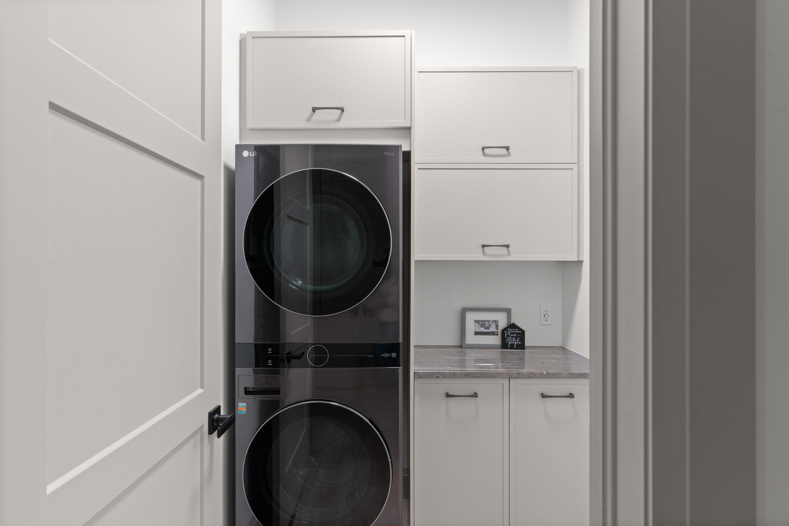 Laundry room with stacked washer and dryer and built-in cabinetry photographed for a Kingston builder portfolio