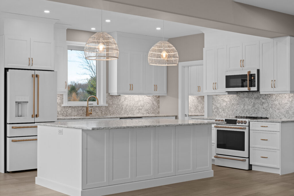 Bright white kitchen with a large island, rattan pendants, and beautiful countertops.